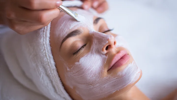Close-up of a skin care specialist applying a facial mask to a client's face, demonstrating expert skincare treatment.