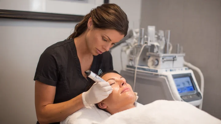 Skin care specialist performing a facial treatment with a modern device on a client in a professional clinic.