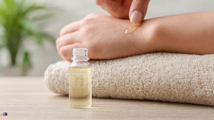 A person applying oil to their forearm for a patch test, with a small bottle of oil on a soft towel background.